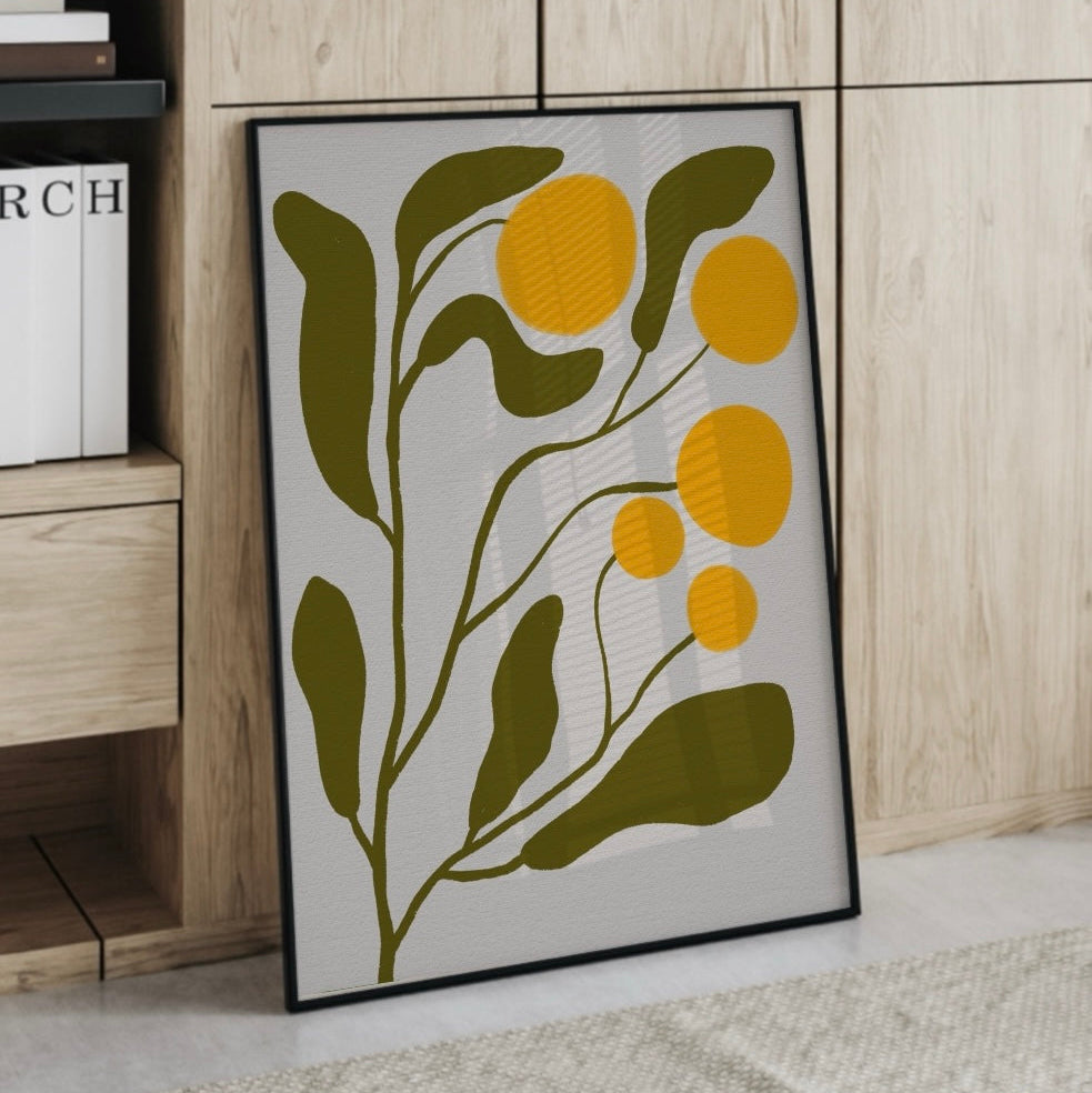 En inramad abstrakt mimosa-poster lutandes mot ett skåp i ett ljust och modernt rum.