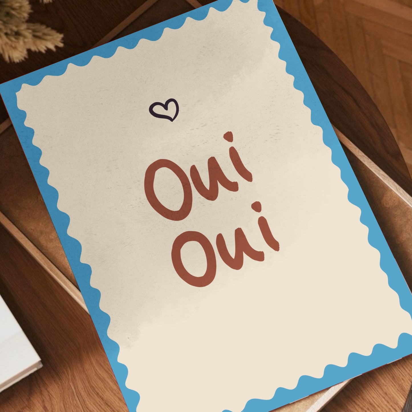 Handmålad illustration med texten Oui Oui liggande på en naturlig träyta i ett ljust skandinaviskt hem.