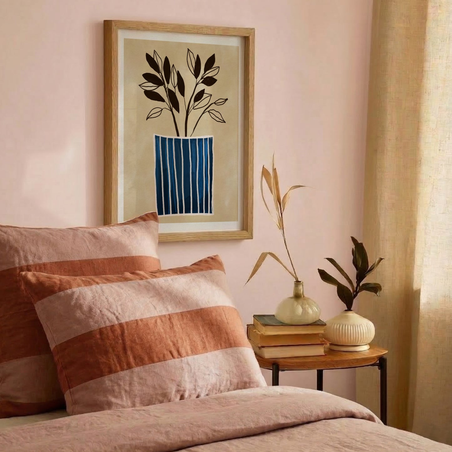 Minimalistisk väggkonst med blårandig vas – Inramad poster i träram hängandes på en rosa vägg i ett harmoniskt sovrum. Miljöbilden visar en bäddad säng med mjuka linnekuddar i terracotta och rosa ränder som matchar den botaniska tavlan.