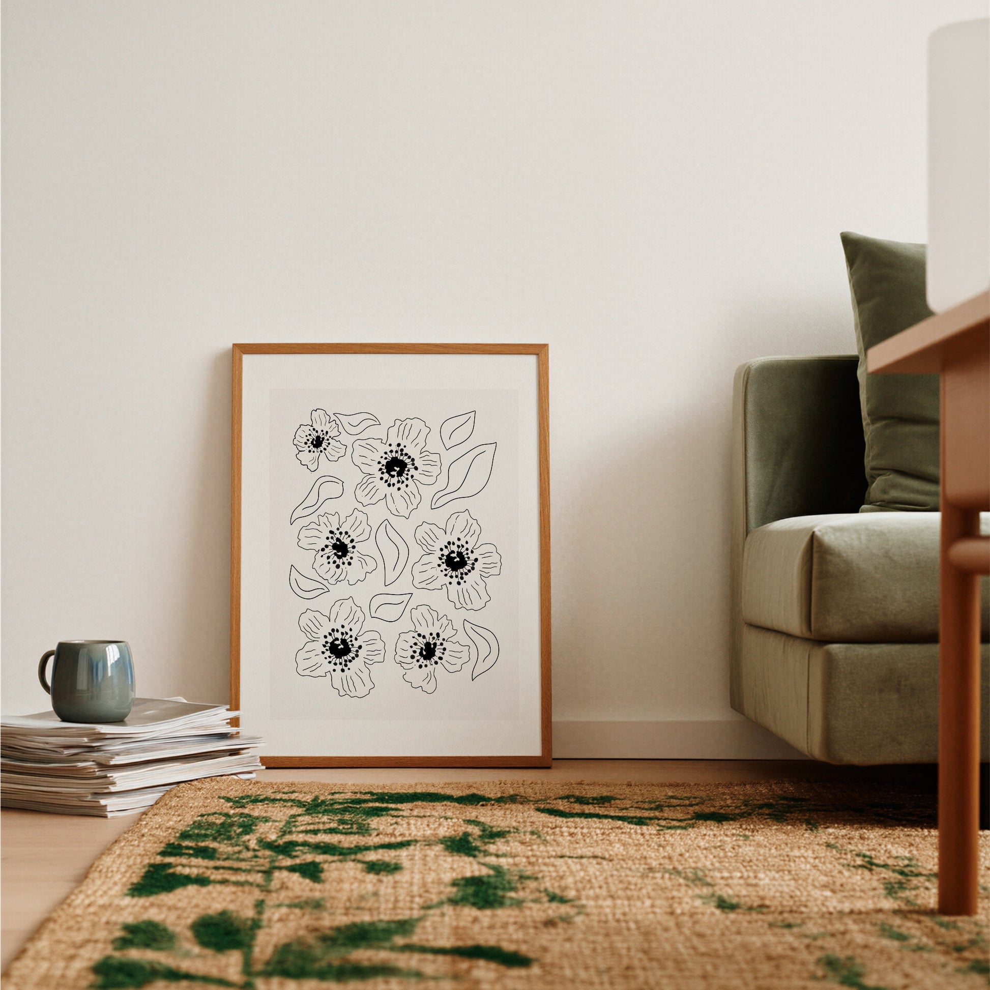 Grafisk vallmoposter lutad mot mörkgrön fåtölj med rustik matta