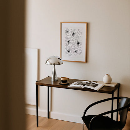 Grafisk vallmoposter upphängd ovanför skrivbord med lampa