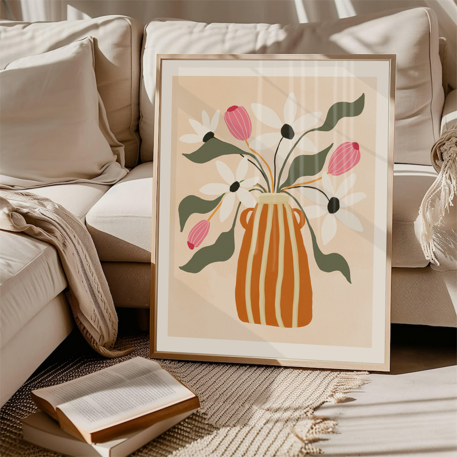 Inramad gouacheposter med vas och blommor, i soffa med kuddar och pläd