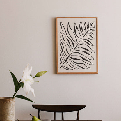 Grafisk palmbladsposter i matplats vid svart bord med blommor