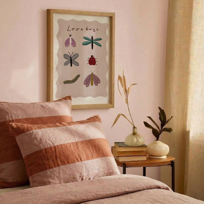 Love Bugs-poster vid sängen med kuddar i varma toner