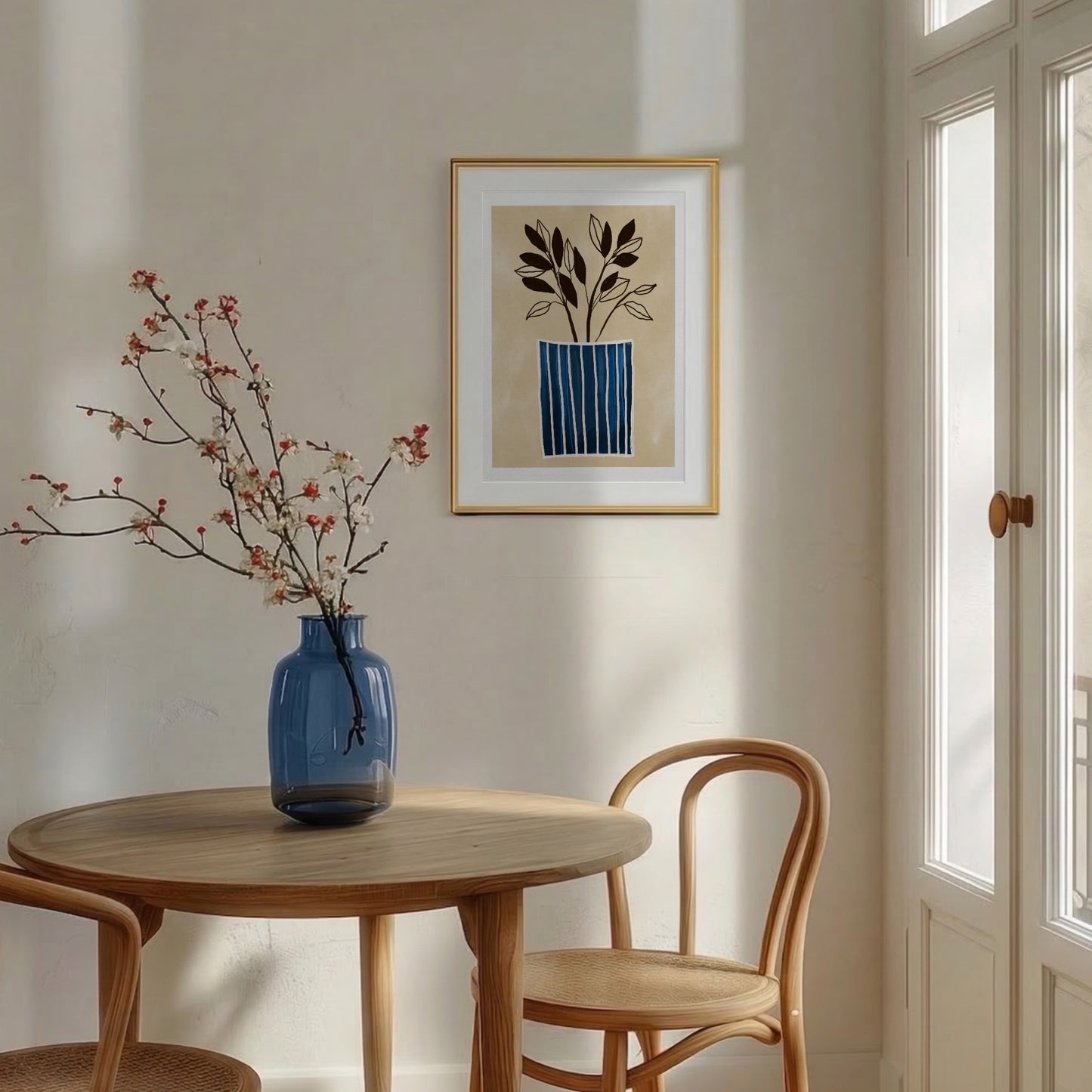 Minimalistisk botanisk poster med blårandig vas, inramad i en ljus träram och hängandes på en vit vägg i en skandinavisk matsal. I förgrunden syns ett träbord med en blå vas och rosa blommor.