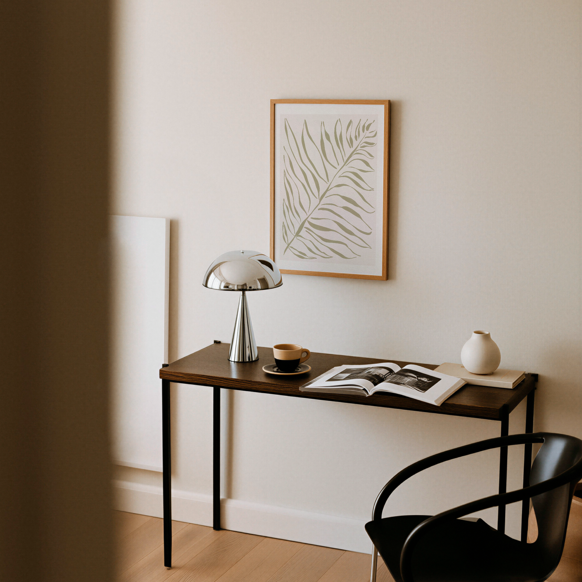 Akvarellposter med palmblad i olivgrönt, upphängd ovanför skrivbord med lampa