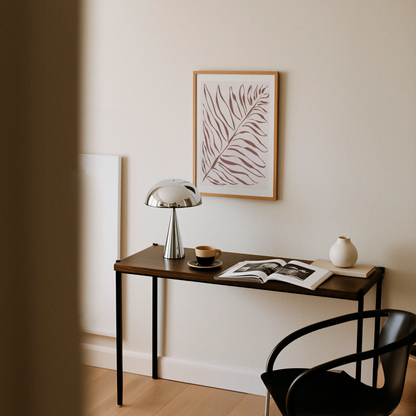Akvarellposter med palmblad i terrakotta, upphängd ovanför avlastningsbord med lampa
