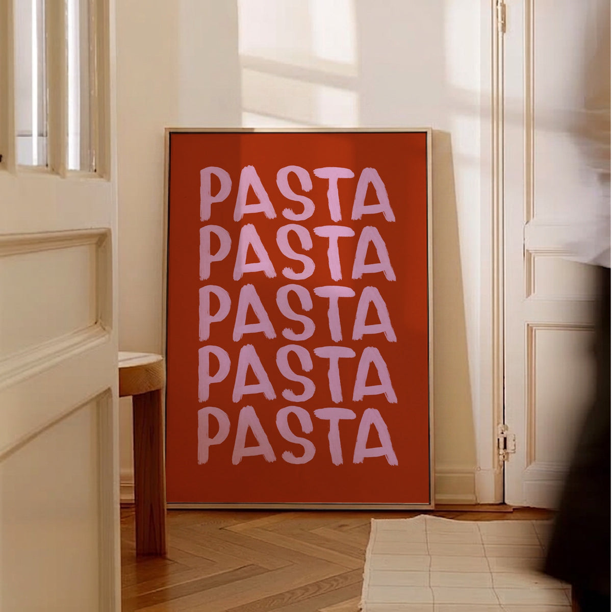 Pastaposter i rostrött och rosa lutad mot väggen i ett ljust rum