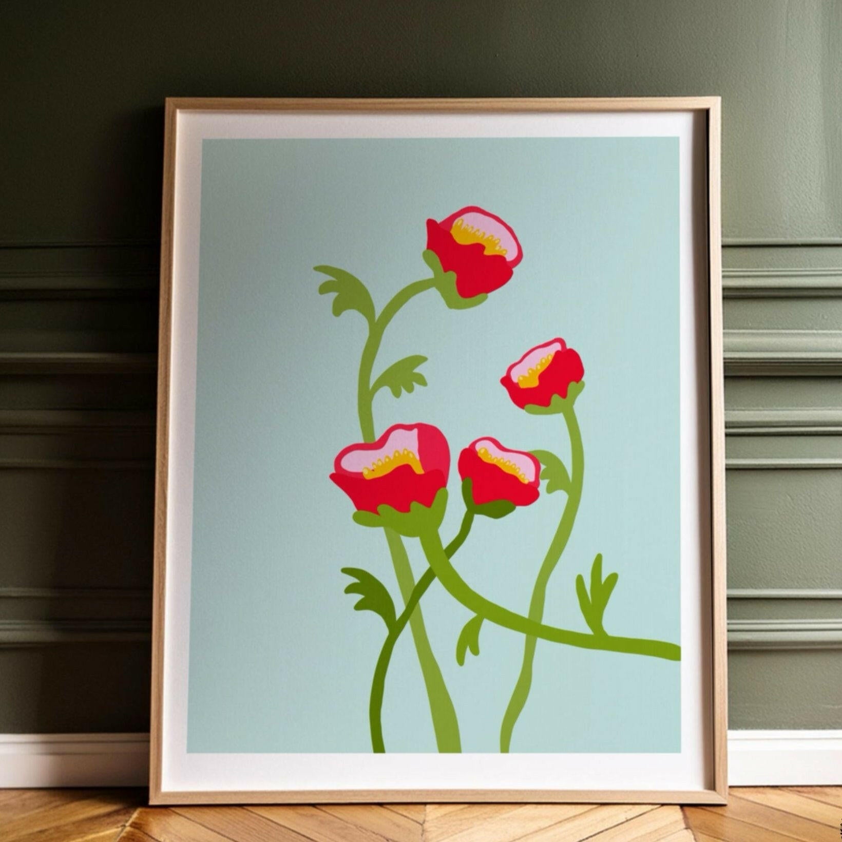 Inramad pionposter med blommotiv i modern grafisk stil lutad mot en mörkgrön panelvägg.