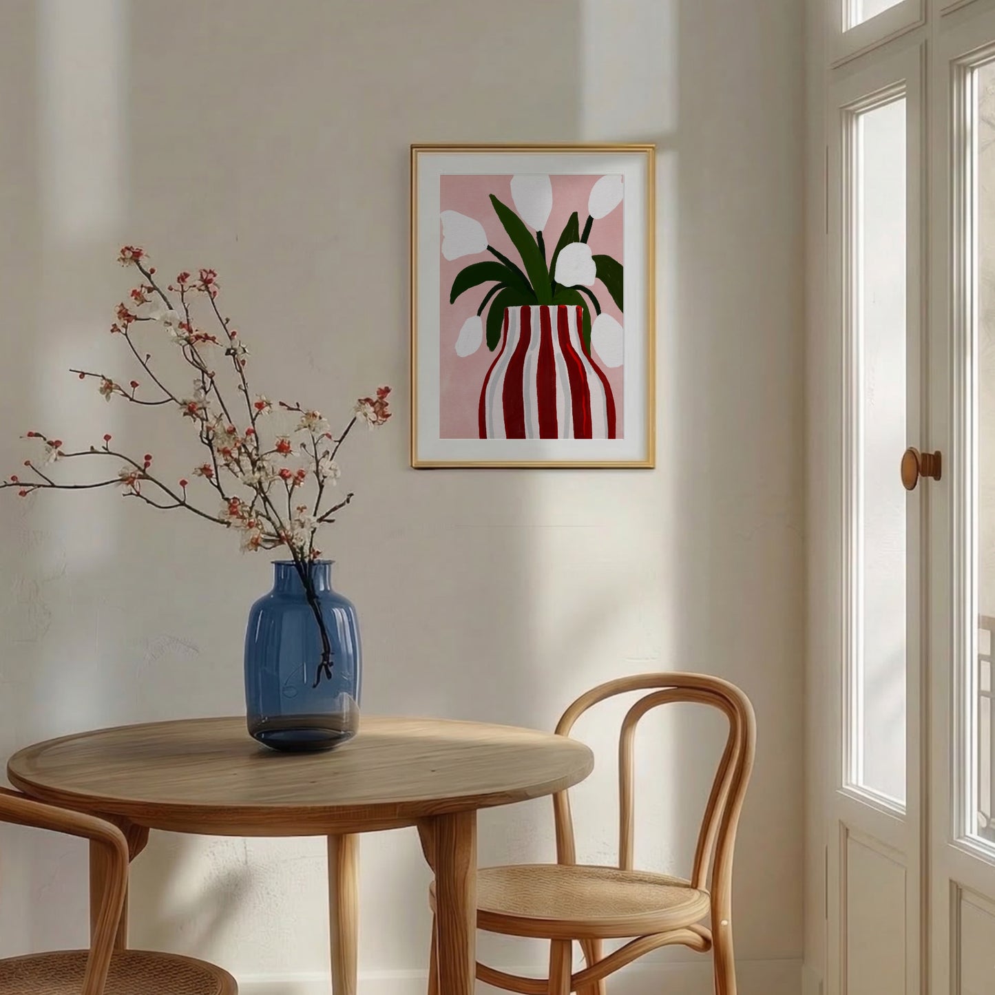 Botanisk tavla i rosa och röda toner inramad i ljus träram, hängd i en matsal med ett runt träbord och matchande trästolar i skandinavisk stil.