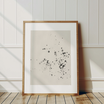 Bläckstänk-postern inramad i en ljus träram som lutar mot en vit panelvägg. Visar hur motivet ger en organisk och tidlös känsla i en skandinavisk inredning.