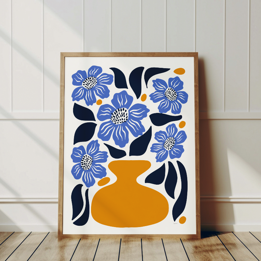 Närbild på vallmopostern som framhäver de blå blommorna i en orange vas, ram i trä lutande mot vit vägg