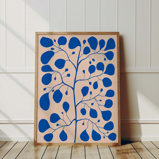 Pilea-tavla i en svart ram som lutar mot en vägg i ett hemmakontor.