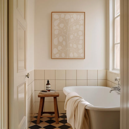 Fysisk poster med vit Pilea-illustration på beige bakgrund inramad i en ljus träram över ett badkar, vilket ger badrummet en harmonisk och modern känsla.