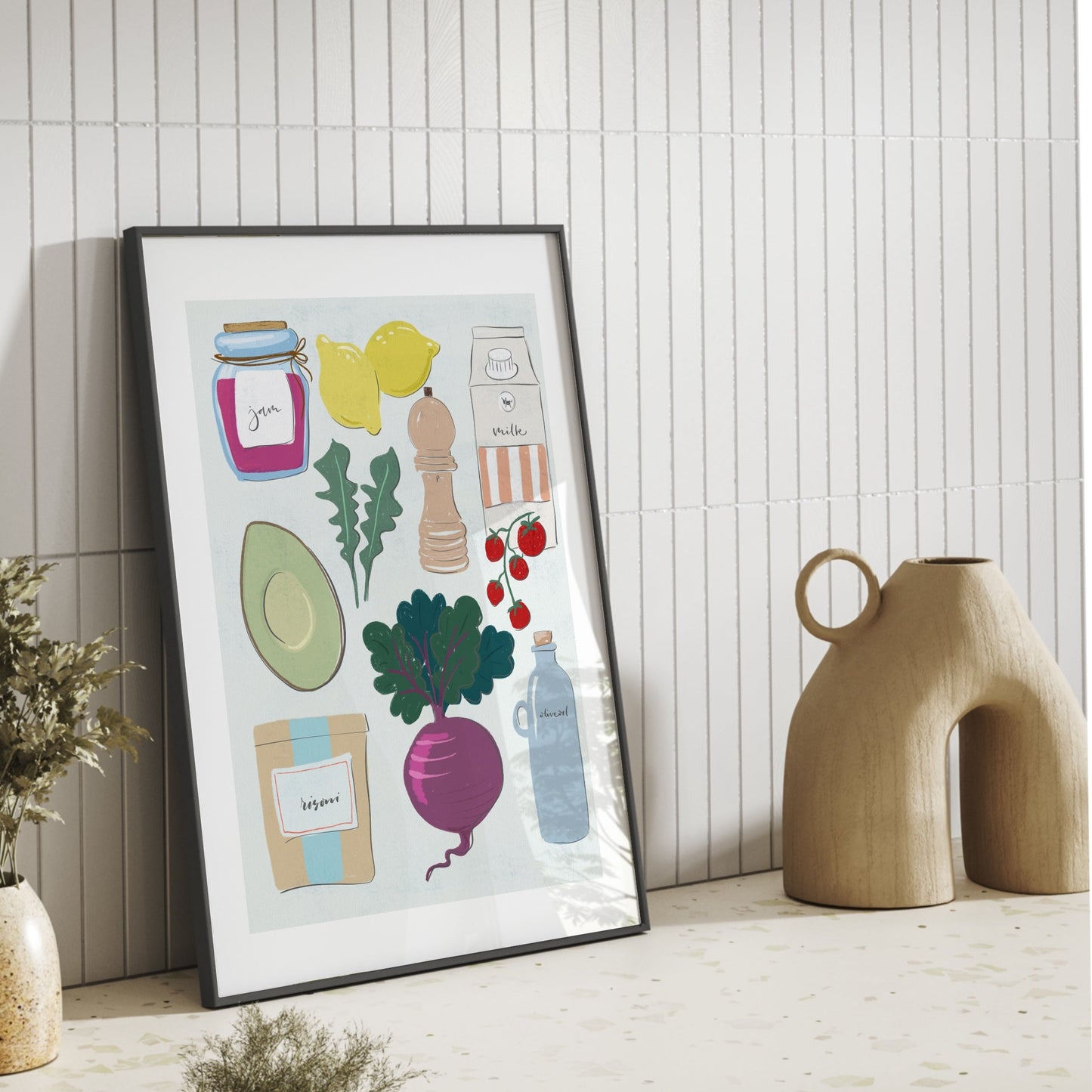 Poster med italienska köksfavoriter lutad mot en vit kakelvägg på en bänkskiva i terrazzo-marmor bredvid en dekorativ beige vas.