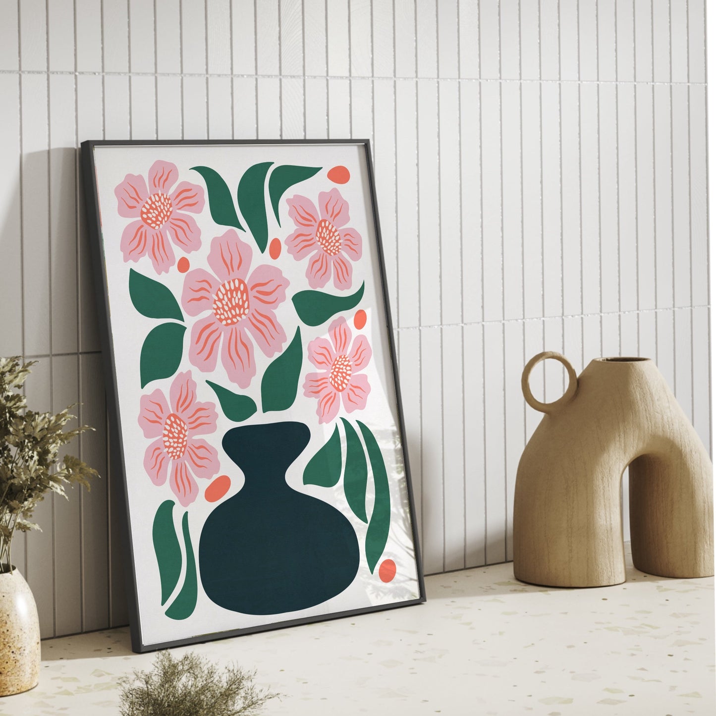 Inredningsinspiration för kök: Botanisk poster med rosa blommor lutad mot en kaklad vägg på en ljus bänk med terrazzo-mönster. Modern och minimalistisk väggkonst.