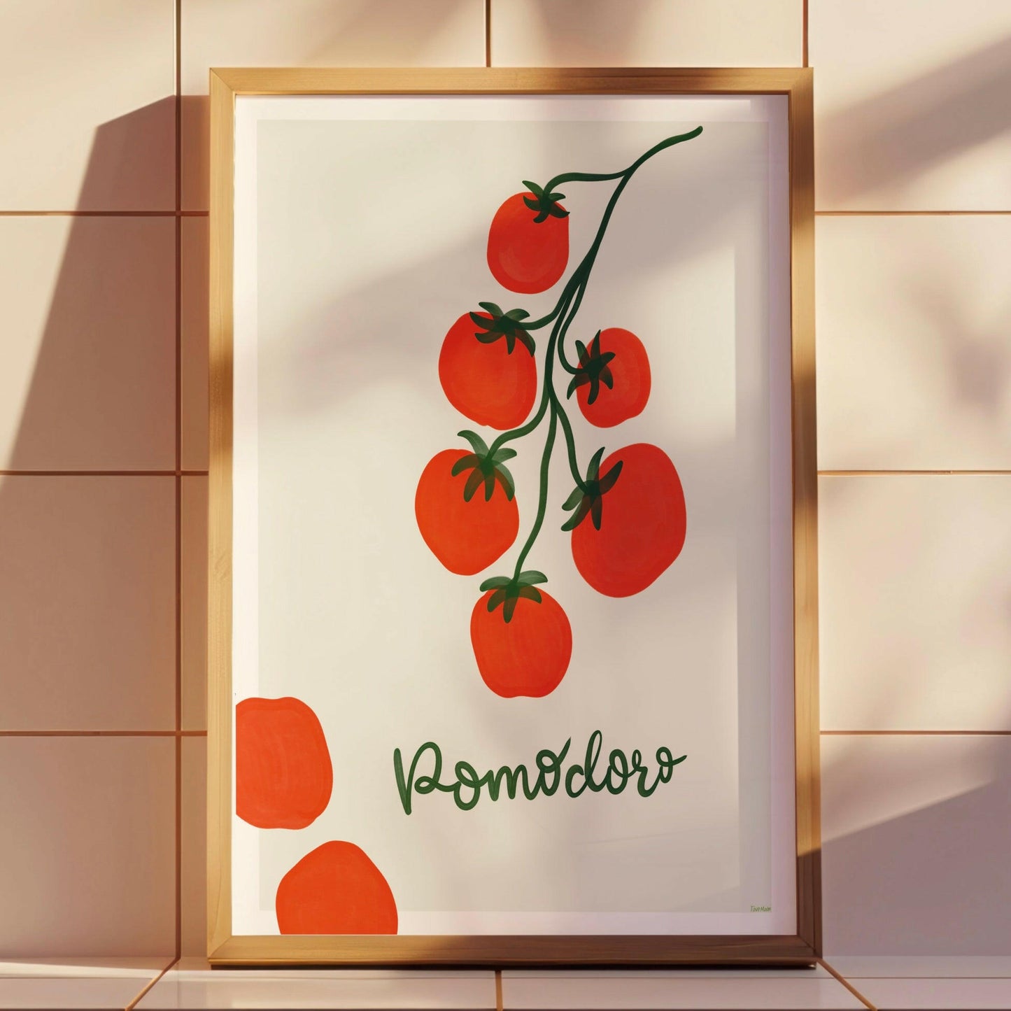 omodoro-postern inramad i en ljus träram lutandes mot en kakelvägg. Visar hur den färgstarka tomatillustrationen lyfter inredningen och skapar en medelhavskänsla.