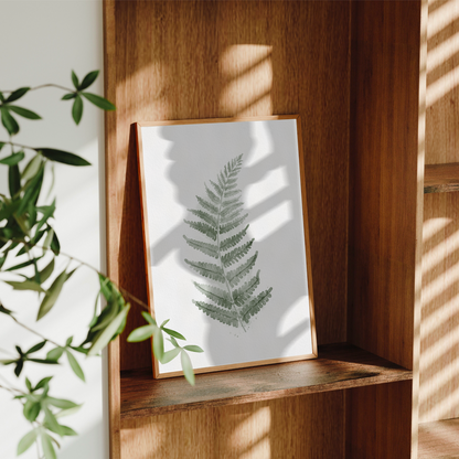  Minimalistisk inredning med grön botaniskt konsttryck i ram som lutar mot väggen 