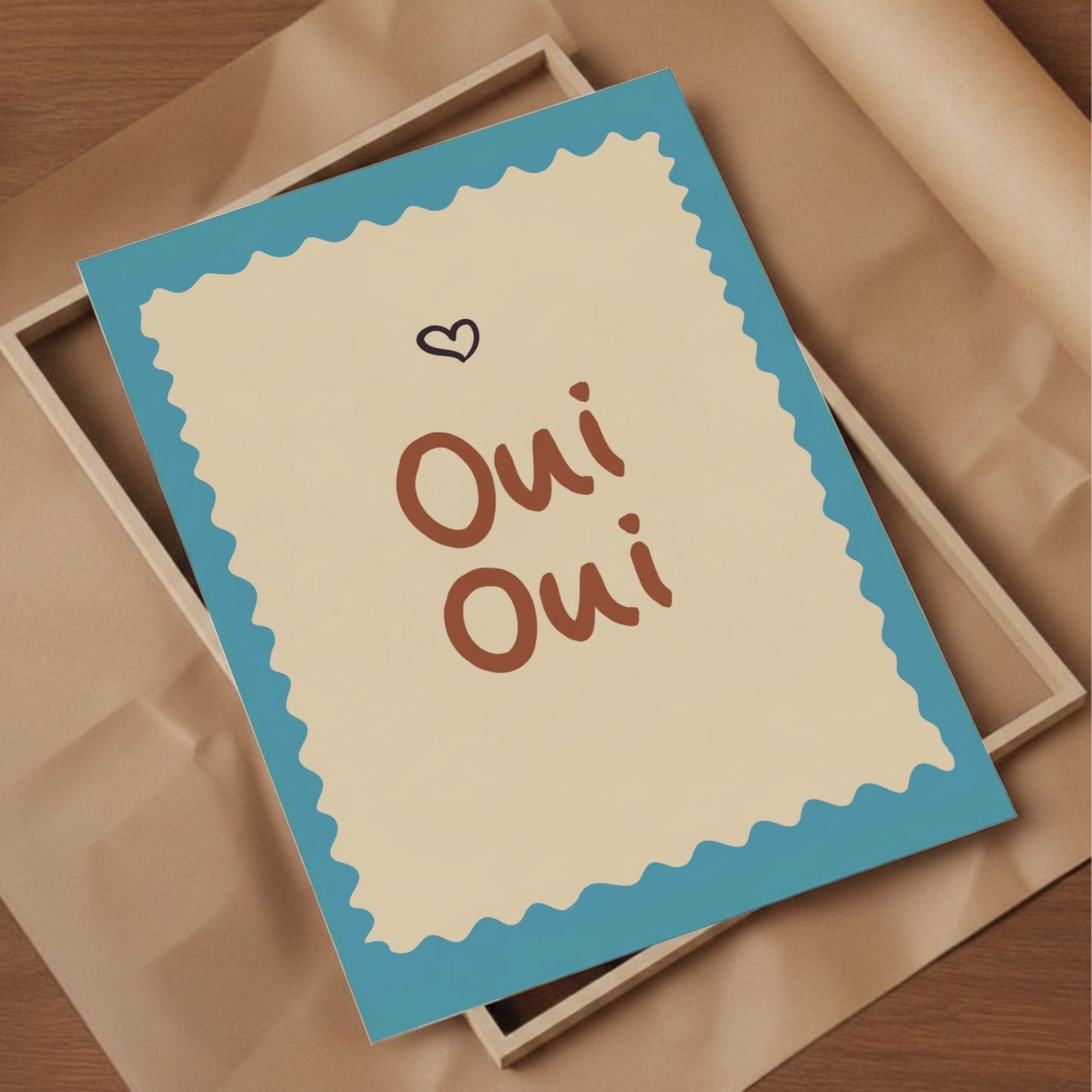 Inramad Oui Oui poster i terracotta och turkos placerad på en ram och brunt inslagningspapper