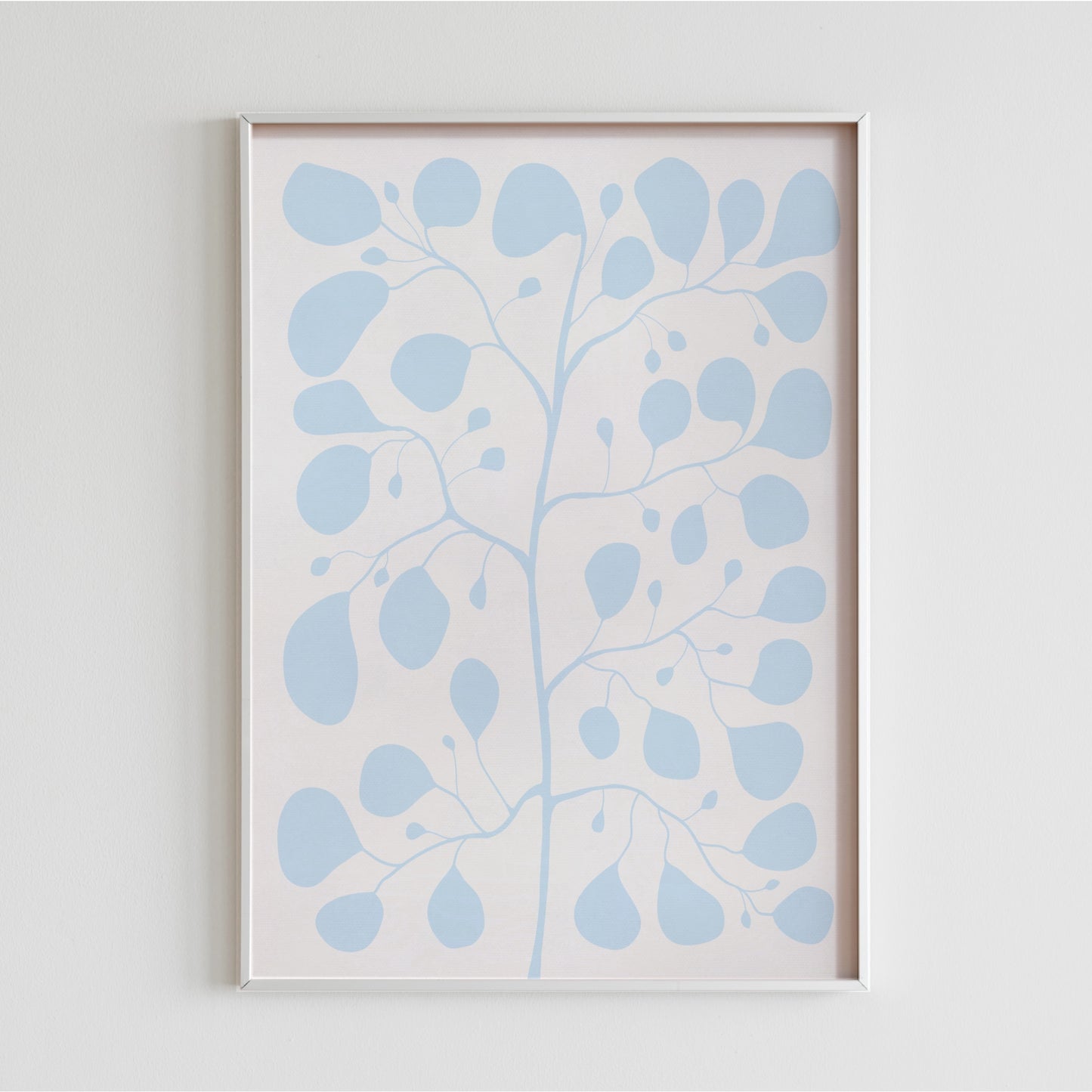 En inramad blå botanisk poster Pilea Fig Cool Blue placerad i ett minimalistiskt hem mot en vit ägg