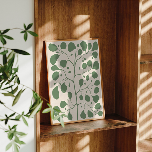 Pilea botanisk poster placerad i en stilren bokhylla av mörkt trä med vackra ljusinsläpp och skuggspel. Minimalistisk inredning med handritad illustration från Tove Malm Studio.