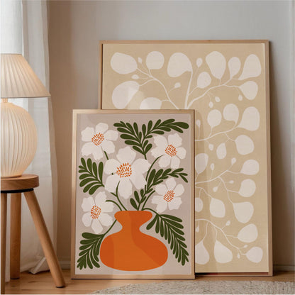 Två fysiska posters från Tove Malm som visar en kombination av Pilea Lucent White och ett färgglatt blommotiv i en orange vas, perfekt inspiration för en personlig tavelvägg.
