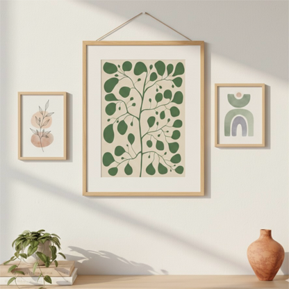 Inspirerande tavelvägg med en stor Pilea & Fig Tree poster upphängd i en magnetisk posterlist i trä, flankerad av två mindre botaniska linjeteckningar i ljusa träramar. Modern minimalistisk inredning med en bohemisk underton och dämpade pasteller från Tove Malm Studio.