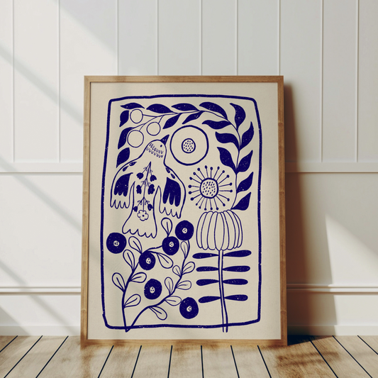 Stor blå fågelposter inramad i trä och lutad mot en vit panelvägg på ett ljust trägolv i ett skandinaviskt hem.