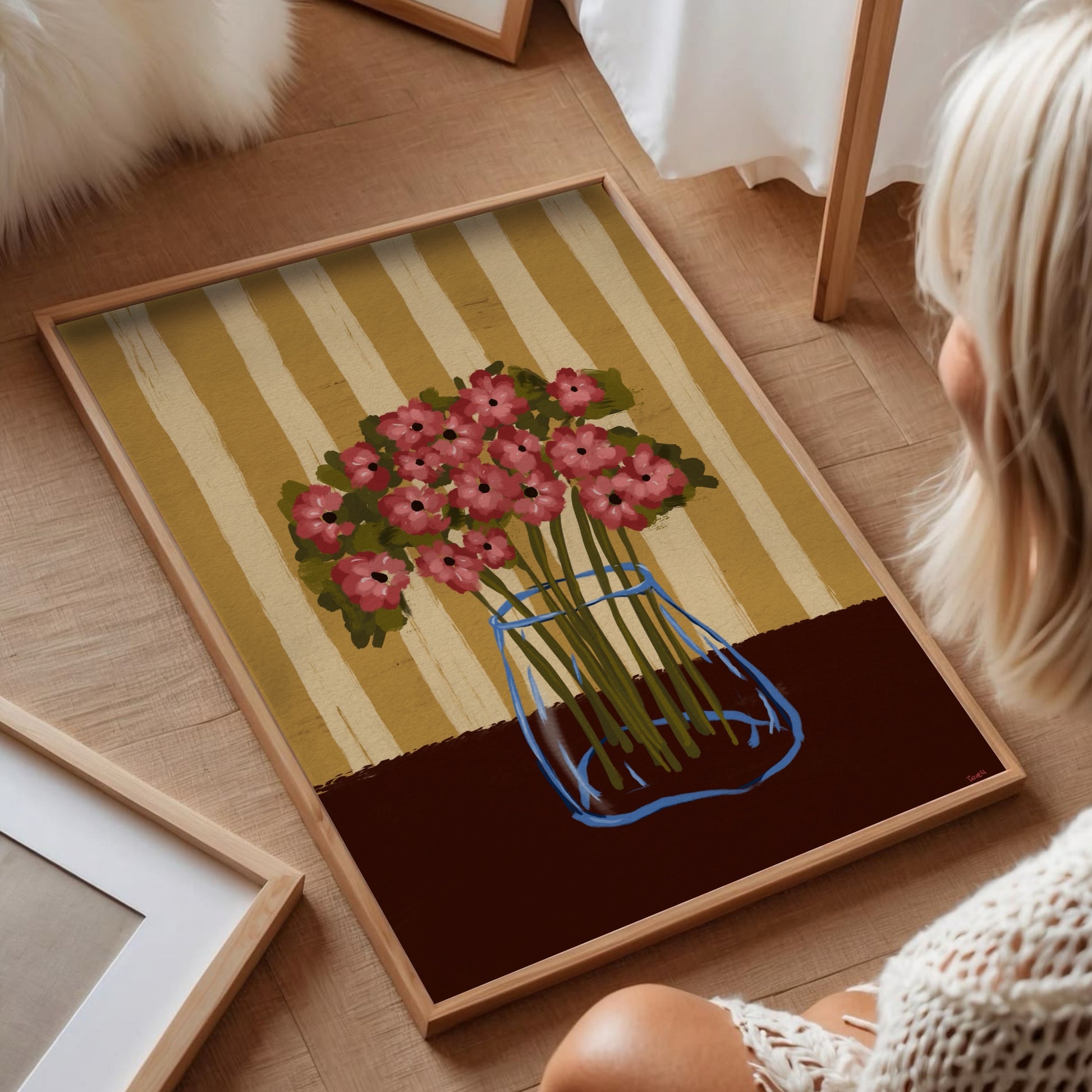 Inramad vallmo-poster liggande på ljust parkettgolv i ett bohemiskt hem med naturligt ljus.